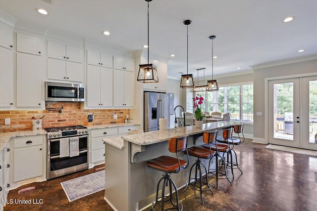 kitchen featuring a kitchen island with sink, hanging light fixtures, white cabinets, and premium appliances