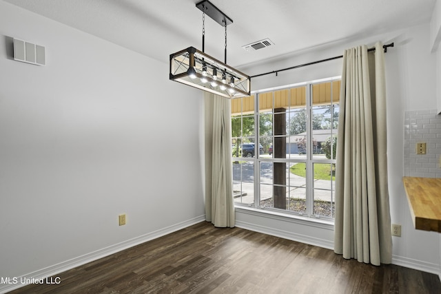 unfurnished dining area with plenty of natural light, dark wood finished floors, and visible vents