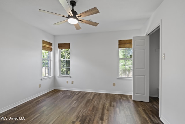 unfurnished room with baseboards, a ceiling fan, and dark wood-style flooring
