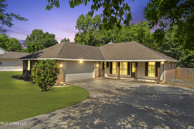 single story home featuring brick siding, a garage, fence, and a yard