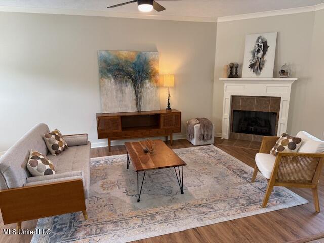 935 Frisky Dr, Brandon, MS 39047 - living room featuring crown molding, ceiling fan, a tile fireplace, wood finished floors, and baseboards