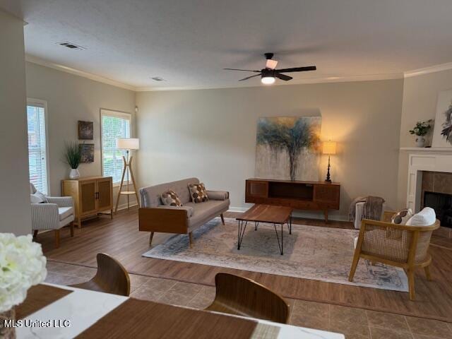 935 Frisky Dr, Brandon, MS 39047 - living area with crown molding, a tiled fireplace, a ceiling fan, wood finished floors, and baseboards