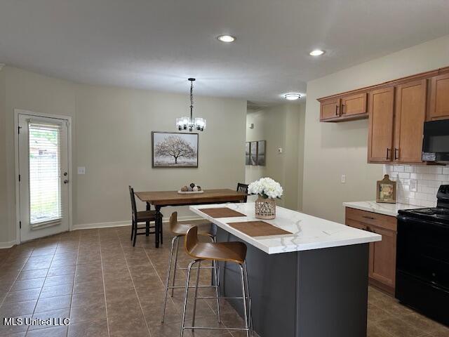 935 Frisky Dr, Brandon, MS 39047 - kitchen with black appliances, brown cabinetry, a kitchen island, decorative backsplash, and hanging light fixtures