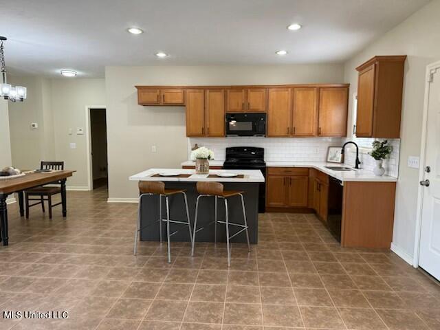 935 Frisky Dr, Brandon, MS 39047 - kitchen with black appliances, brown cabinetry, a sink, tasteful backsplash, and light countertops