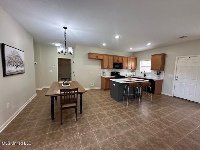 935 Frisky Dr, Brandon, MS 39047 - kitchen featuring black appliances, brown cabinets, a chandelier, light countertops, and a kitchen island
