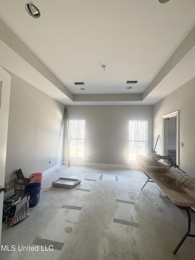 spare room with a raised ceiling, visible vents, plenty of natural light, and baseboards