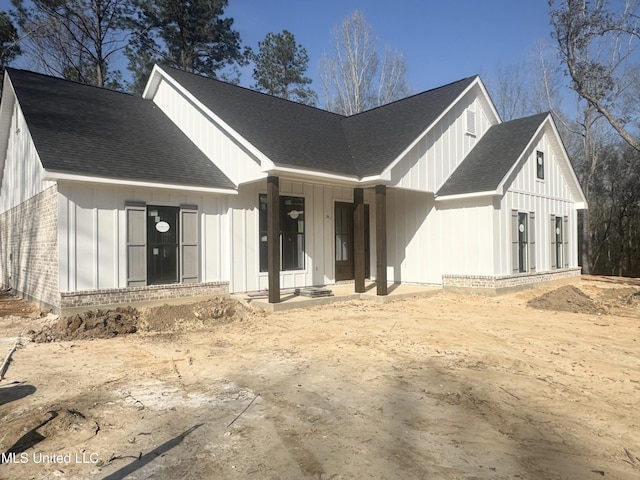 modern inspired farmhouse featuring board and batten siding, brick siding, and a shingled roof