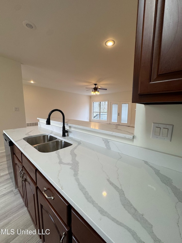 kitchen featuring light stone counters, recessed lighting, stainless steel dishwasher, a sink, and dark brown cabinetry