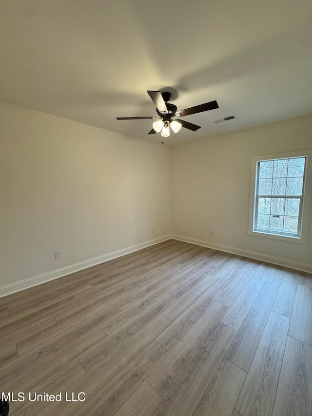 empty room featuring a ceiling fan, baseboards, visible vents, and light wood finished floors