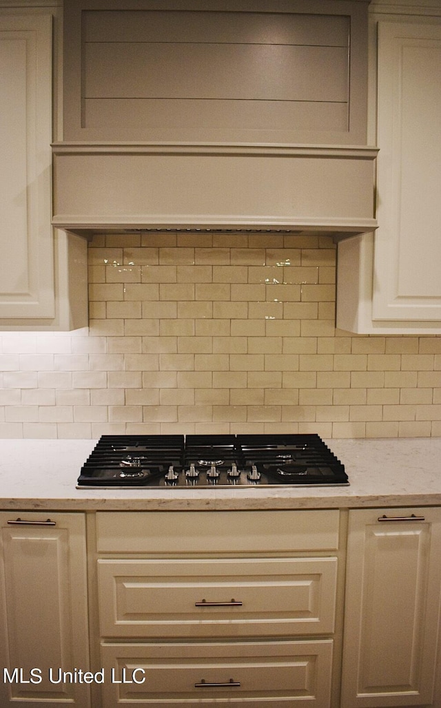 kitchen with light stone counters, black gas cooktop, and decorative backsplash