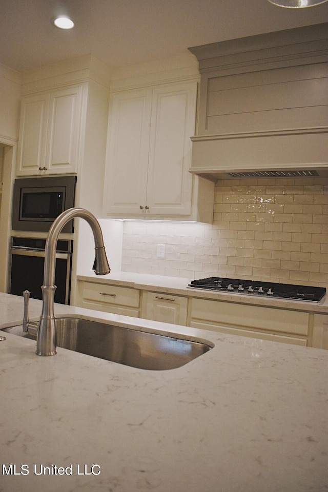 kitchen with decorative backsplash, light stone countertops, sink, and stainless steel appliances