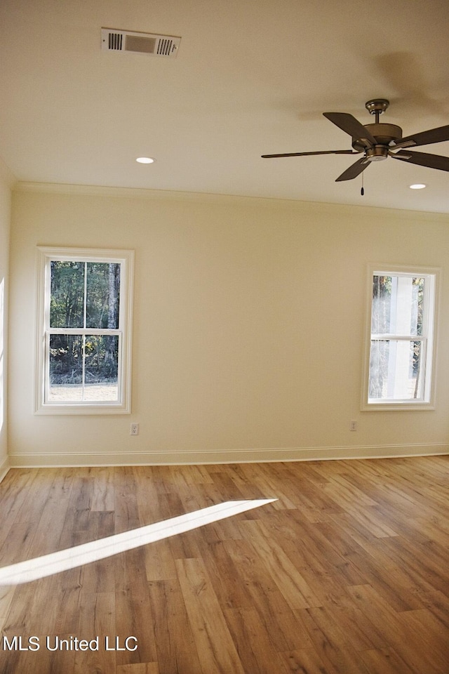 empty room with plenty of natural light, hardwood / wood-style flooring, and ceiling fan