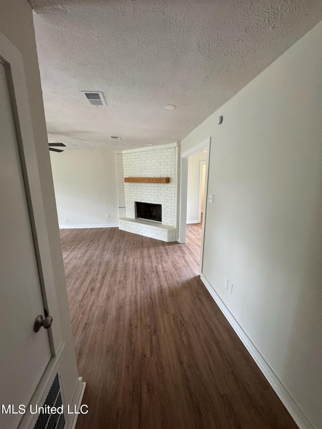 unfurnished living room featuring hardwood / wood-style flooring, a textured ceiling, and a fireplace