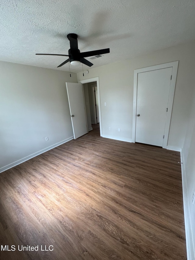 unfurnished bedroom featuring dark wood-type flooring, a textured ceiling, and ceiling fan