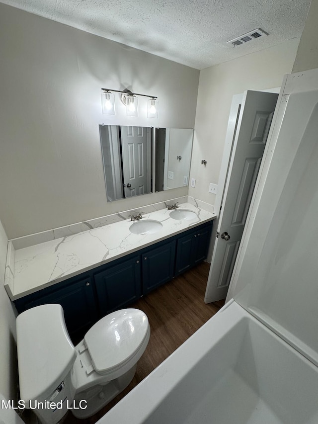 bathroom featuring vanity, toilet, a textured ceiling, and hardwood / wood-style floors