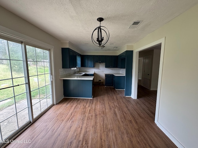 kitchen with hanging light fixtures, backsplash, dark hardwood / wood-style flooring, a textured ceiling, and a chandelier