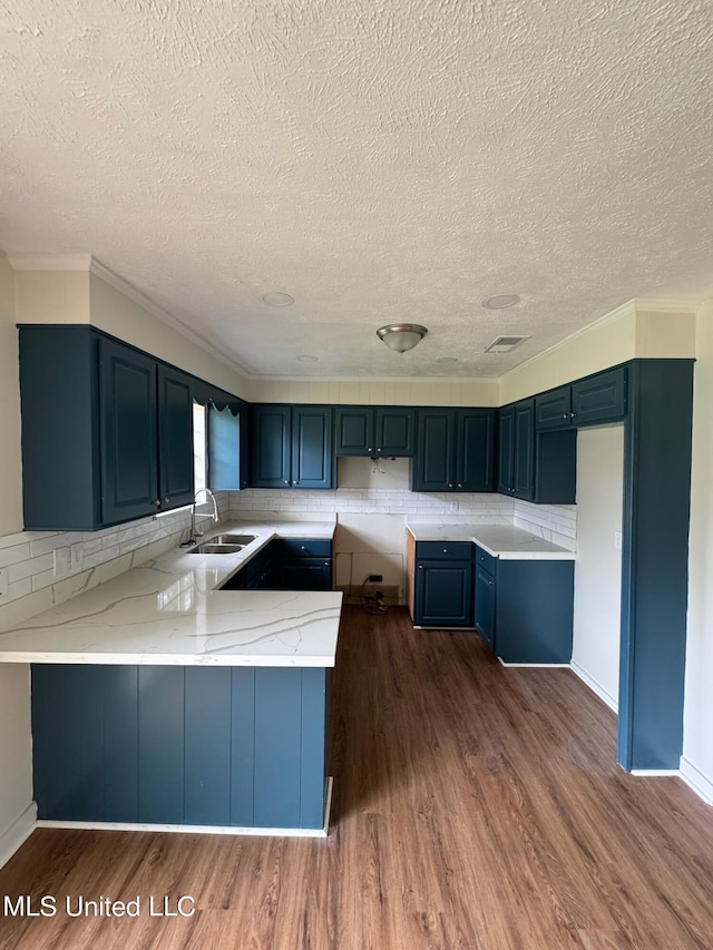 kitchen with dark wood-type flooring, decorative backsplash, sink, and kitchen peninsula