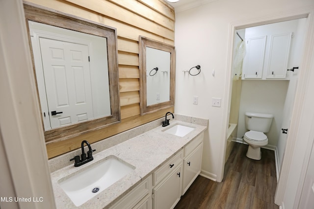 full bathroom featuring a sink, toilet, double vanity, and wood finished floors