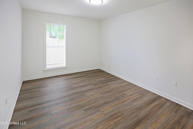 empty room with dark wood-style flooring and baseboards
