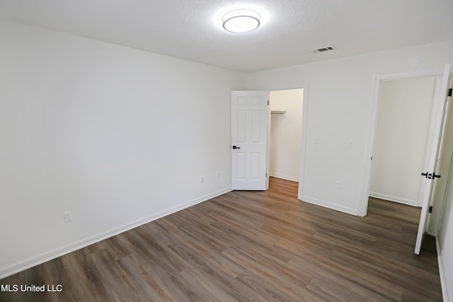 unfurnished bedroom with visible vents, baseboards, a textured ceiling, and dark wood finished floors