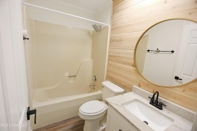 bathroom with toilet, wooden walls, bathtub / shower combination, vanity, and wood finished floors