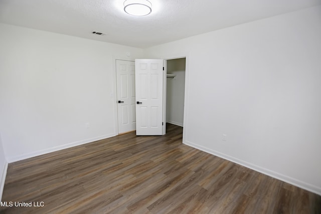 unfurnished bedroom featuring visible vents, baseboards, a closet, and dark wood-style floors