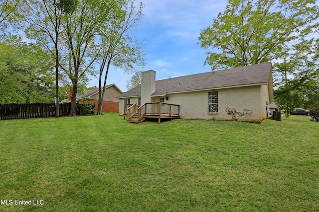rear view of property featuring a lawn, fence, cooling unit, brick siding, and a wooden deck