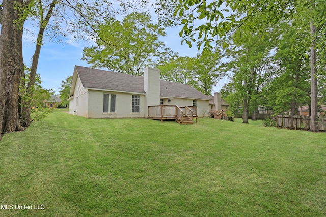 back of house featuring a yard, a wooden deck, fence, and a chimney