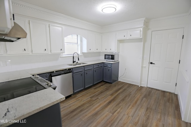 kitchen with a sink, white microwave, gray cabinetry, wood finished floors, and stainless steel dishwasher