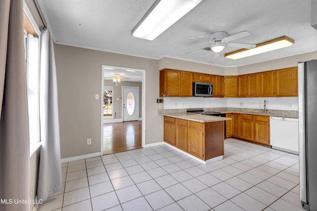 7105 Mandarin Dr, Biloxi, MS 39532 - kitchen featuring ceiling fan, stainless steel appliances, a textured ceiling, a peninsula, and brown cabinets