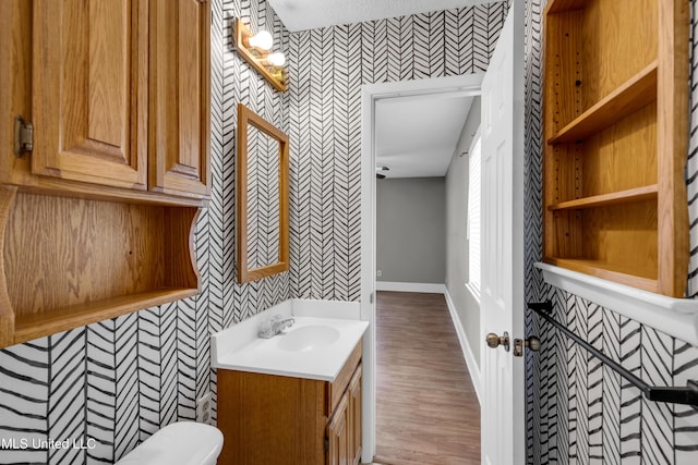 7105 Mandarin Dr, Biloxi, MS 39532 - half bathroom featuring wallpapered walls, vanity, and wood finished floors