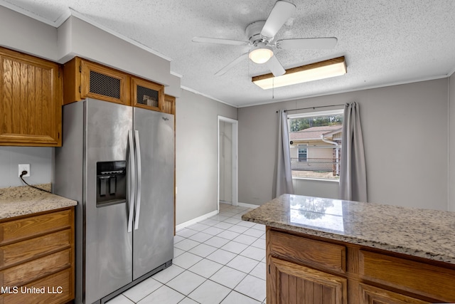 7105 Mandarin Dr, Biloxi, MS 39532 - kitchen with stainless steel fridge, brown cabinetry, ceiling fan, light tile patterned floors, and a textured ceiling