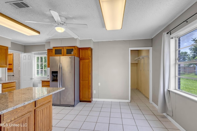 7105 Mandarin Dr, Biloxi, MS 39532 - kitchen with stainless steel refrigerator with ice dispenser, a ceiling fan, brown cabinetry, a textured ceiling, and light stone countertops