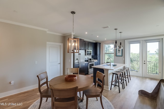 dining room featuring french doors, crown molding, sink, light hardwood / wood-style floors, and a chandelier