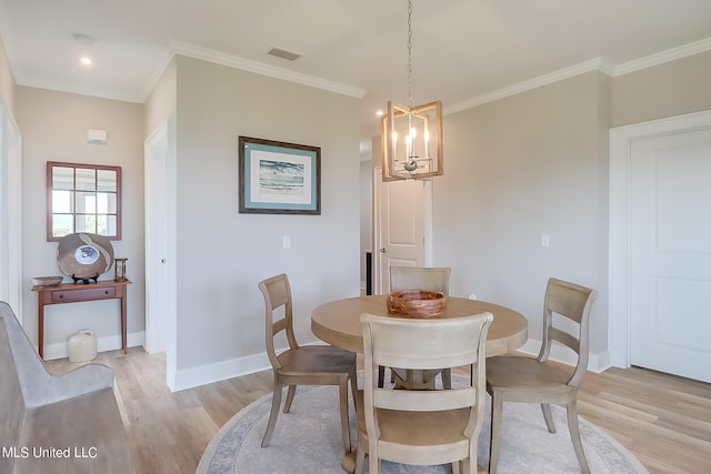 dining room with ornamental molding, light wood-type flooring, and an inviting chandelier