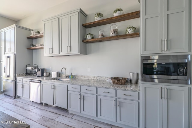 kitchen featuring gray cabinetry, light stone countertops, sink, and appliances with stainless steel finishes