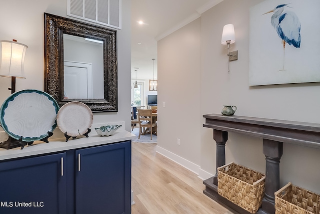 hallway featuring light wood-type flooring and crown molding