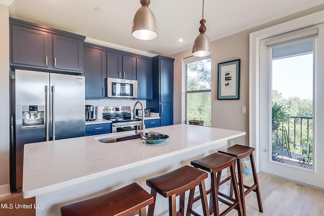 kitchen featuring sink, decorative light fixtures, a kitchen bar, a kitchen island with sink, and appliances with stainless steel finishes