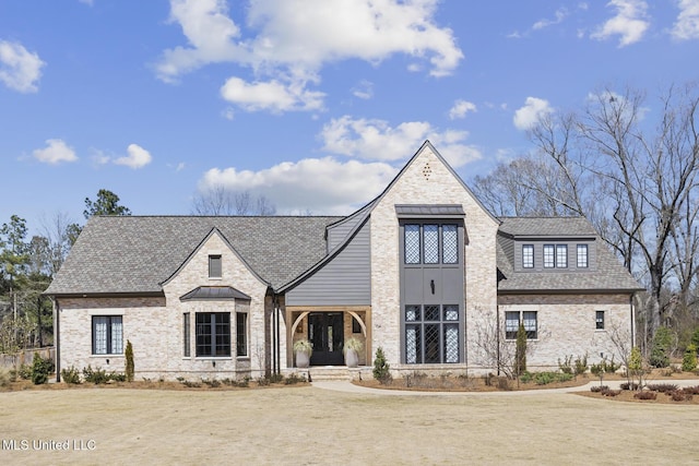 view of front facade featuring brick siding and roof with shingles