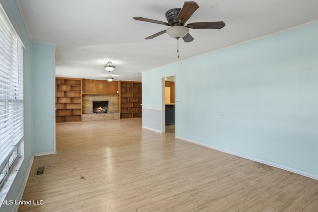 unfurnished living room with light wood-style flooring, a brick fireplace, visible vents, and crown molding