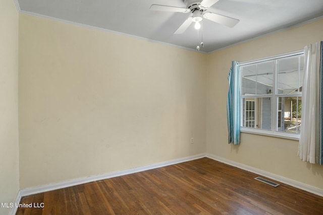 spare room with dark wood-type flooring, a ceiling fan, visible vents, baseboards, and crown molding