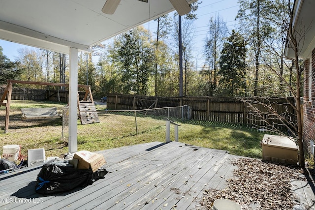 wooden terrace with ceiling fan, a yard, a playground, and a fenced backyard