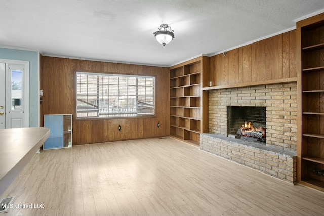 unfurnished living room featuring built in shelves, wood walls, and wood finished floors