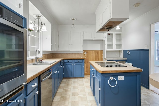 kitchen featuring appliances with stainless steel finishes, wainscoting, a sink, and blue cabinetry