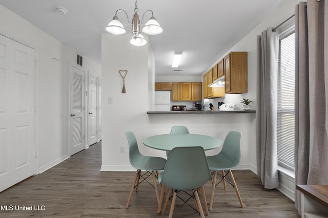 dining area featuring dark hardwood / wood-style flooring and an inviting chandelier