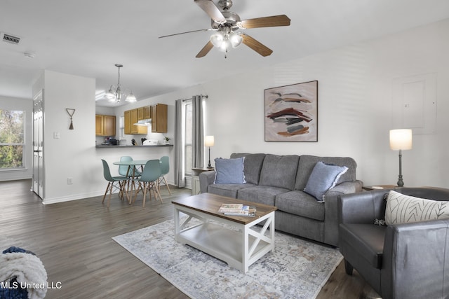 living room with ceiling fan with notable chandelier and dark hardwood / wood-style flooring