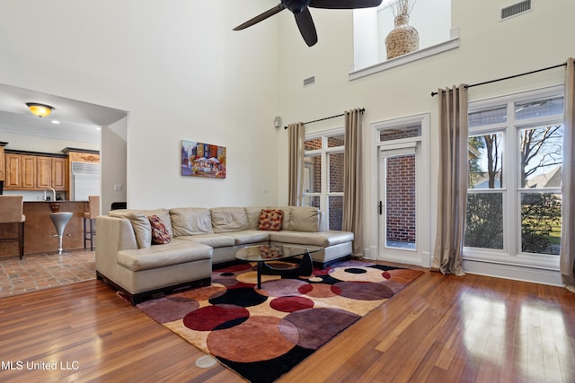 living room featuring ceiling fan, a towering ceiling, and dark hardwood / wood-style floors