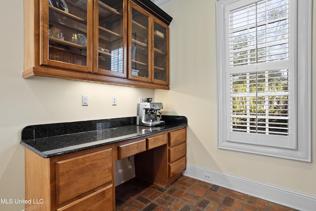 interior space featuring built in desk, crown molding, and dark stone counters