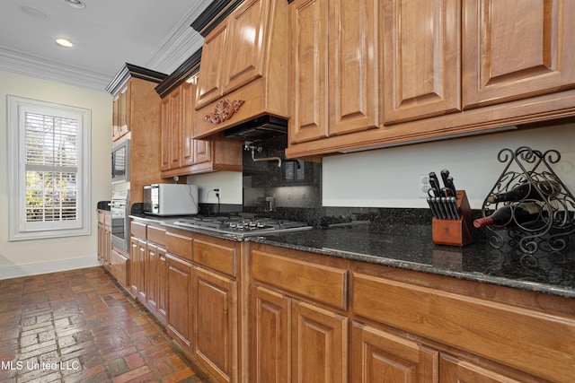 kitchen with decorative backsplash, stainless steel appliances, ornamental molding, and dark stone countertops