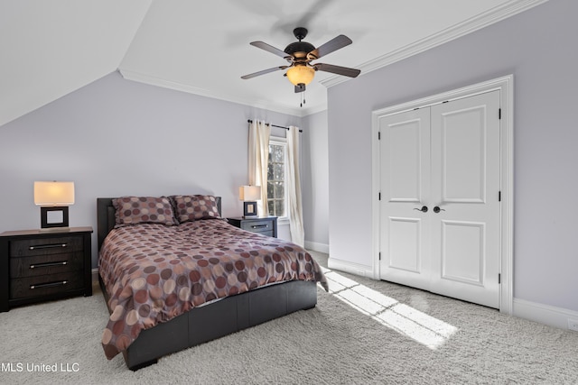 carpeted bedroom featuring ceiling fan, vaulted ceiling, ornamental molding, and a closet